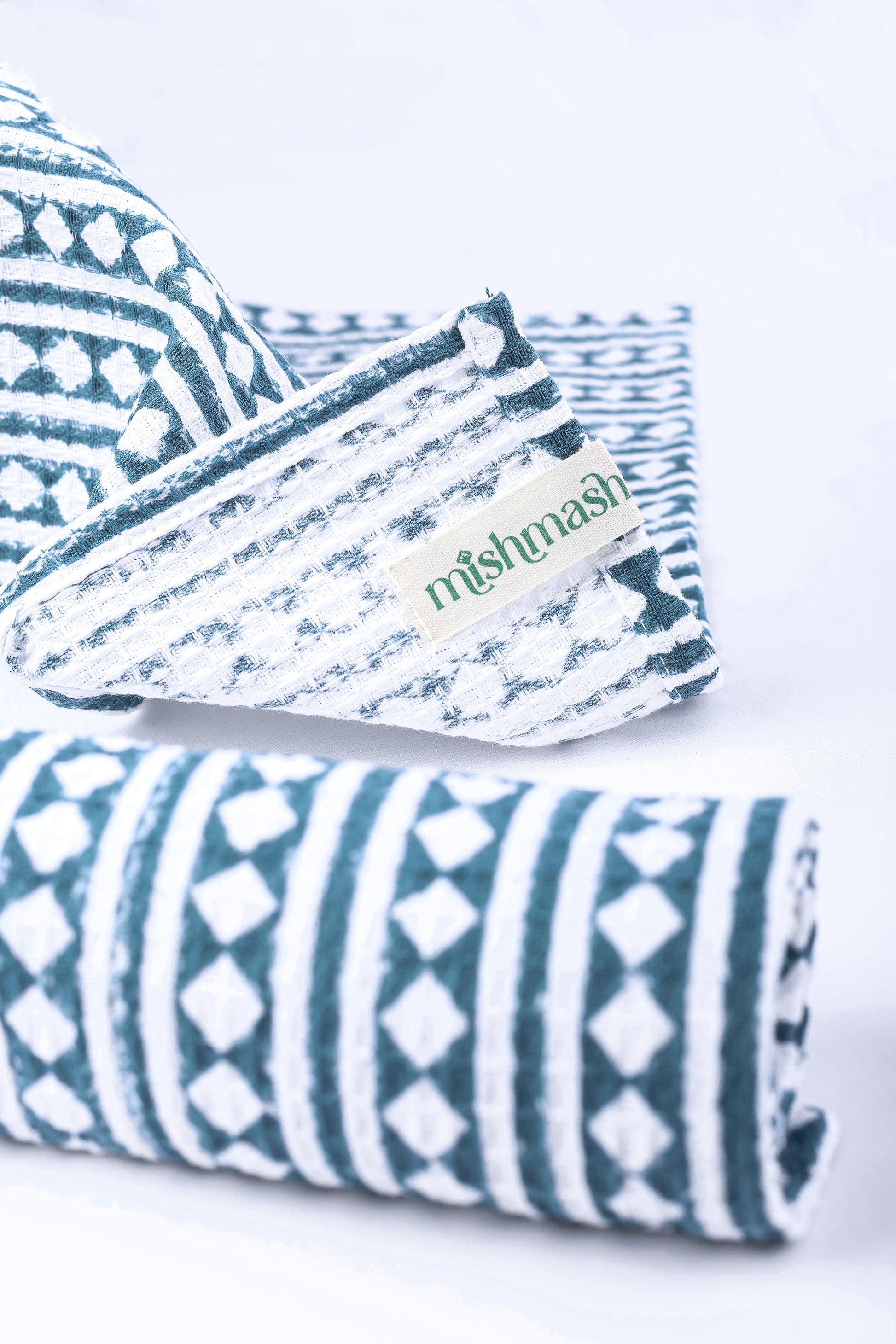 Folded hand napkins with blue and white print and 'mishmash' branding on a white background.