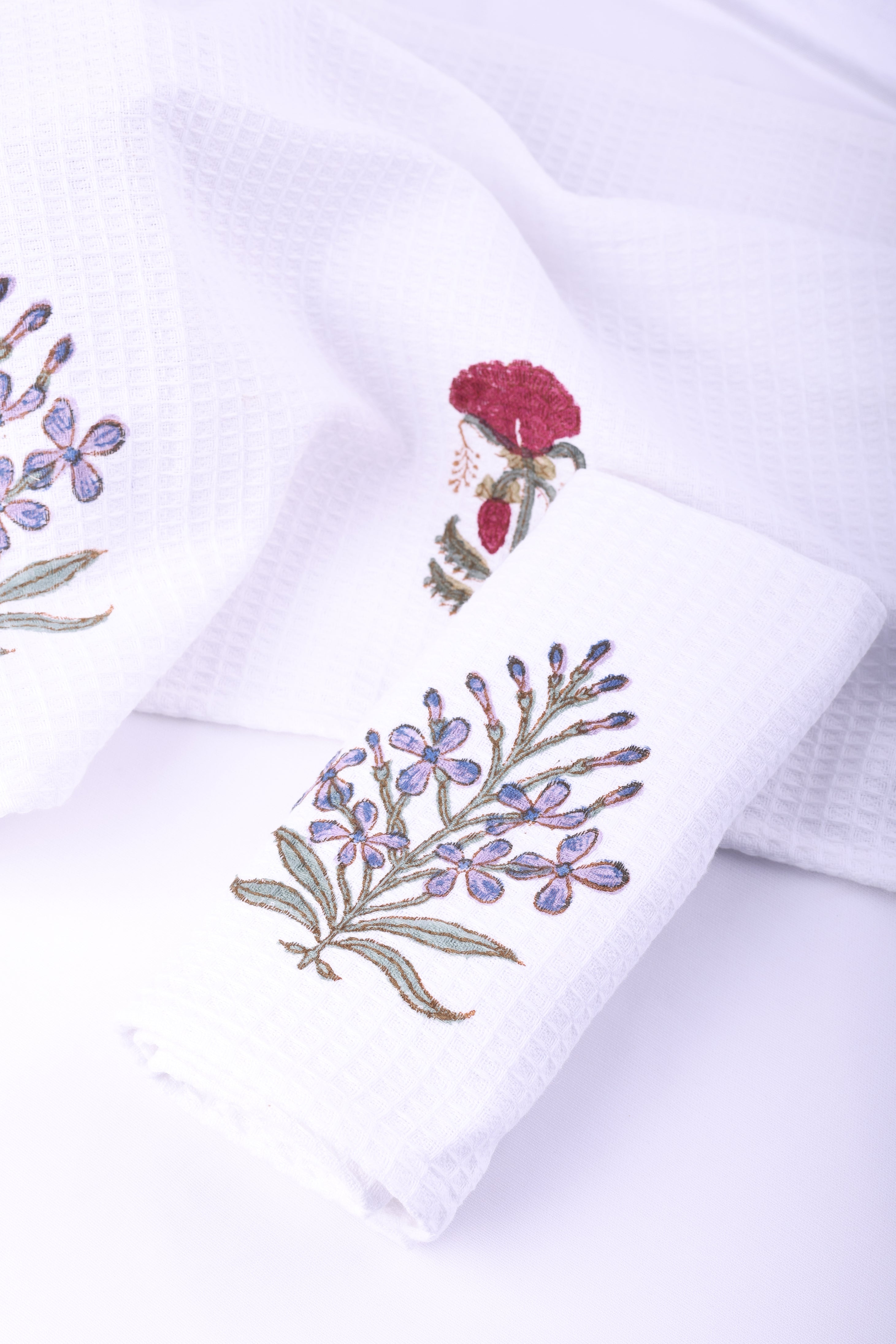 White hand towels with block printed floral designs on a white background. Quick dry hand towels. Towel sets.