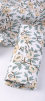 Folded floral cotton hand towels with green and yellow print on a white background. Buy bath linen online.