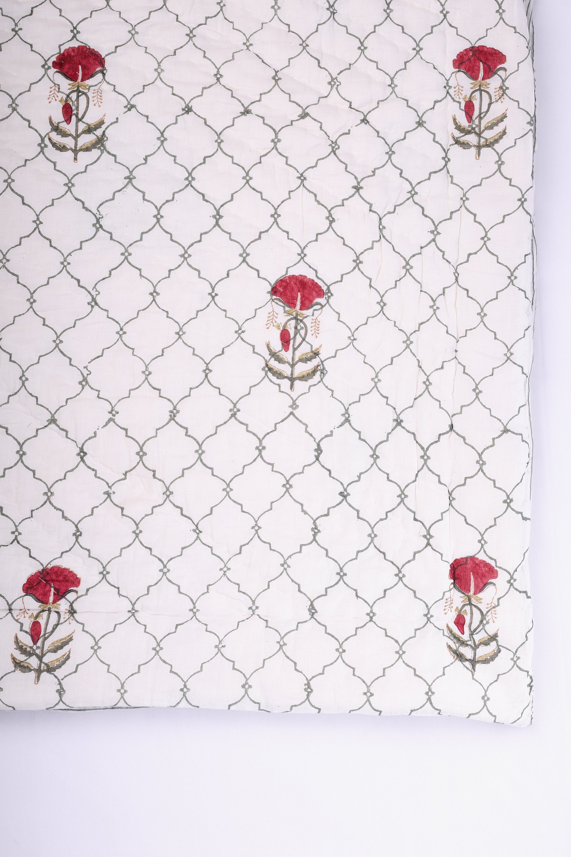 White winter quilt with red and green jaal pattern on a white background. All seasons jaipur razai. 