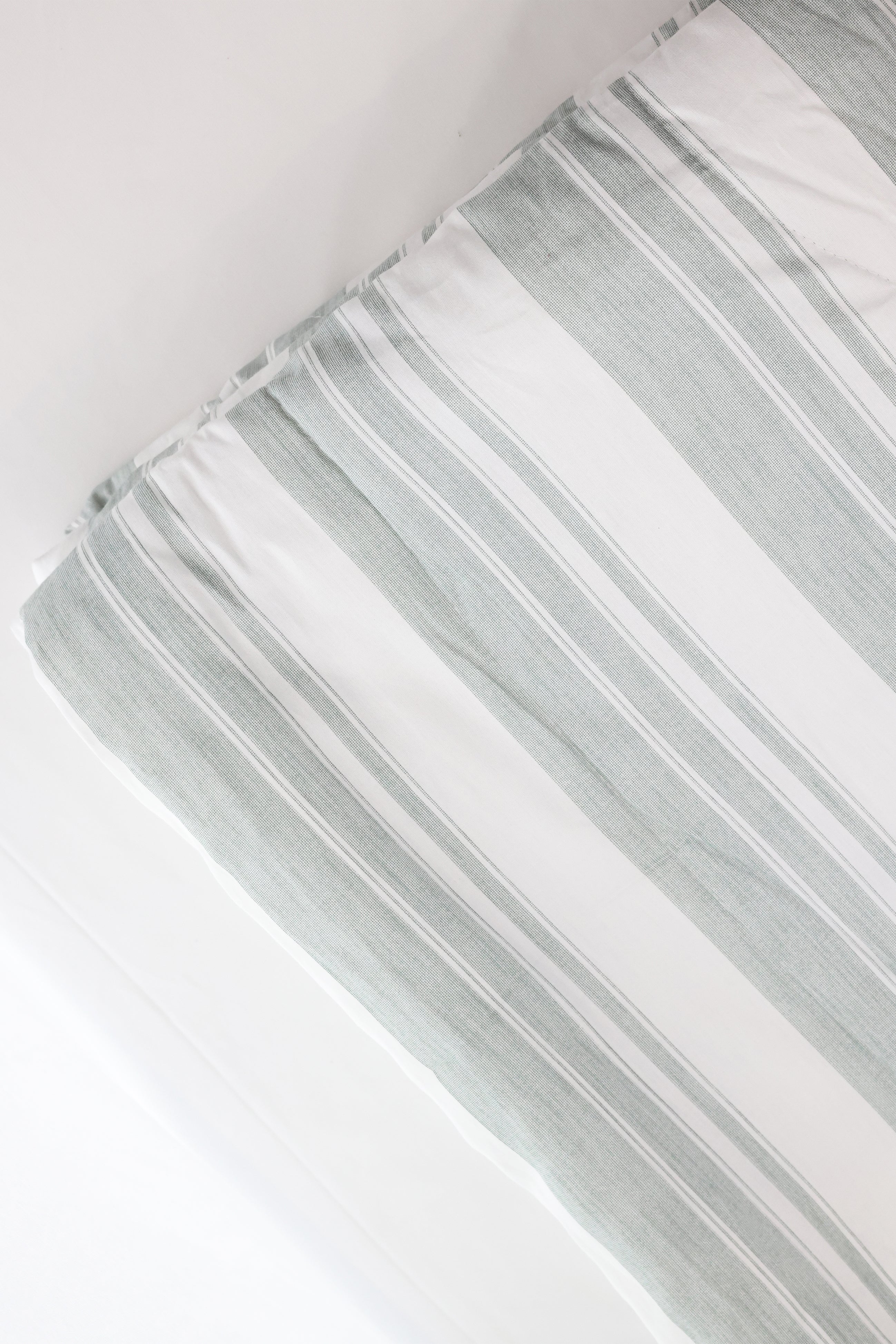 Close-up of a striped winter comforter with white and ash green lines on a white base. Pure cotton winter comforter.