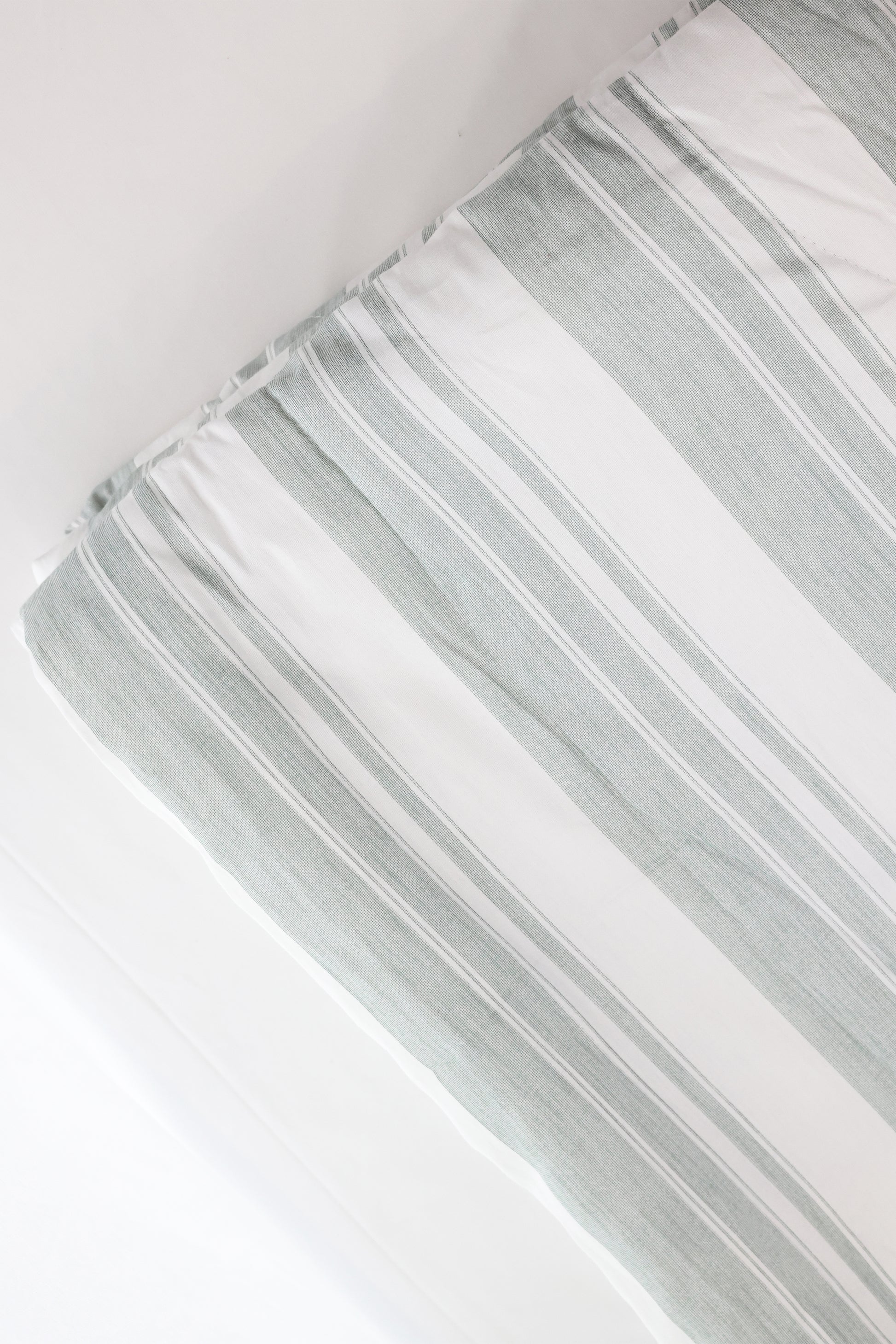 Close-up of a striped winter comforter with white and ash green lines on a white base. Pure cotton winter comforter.