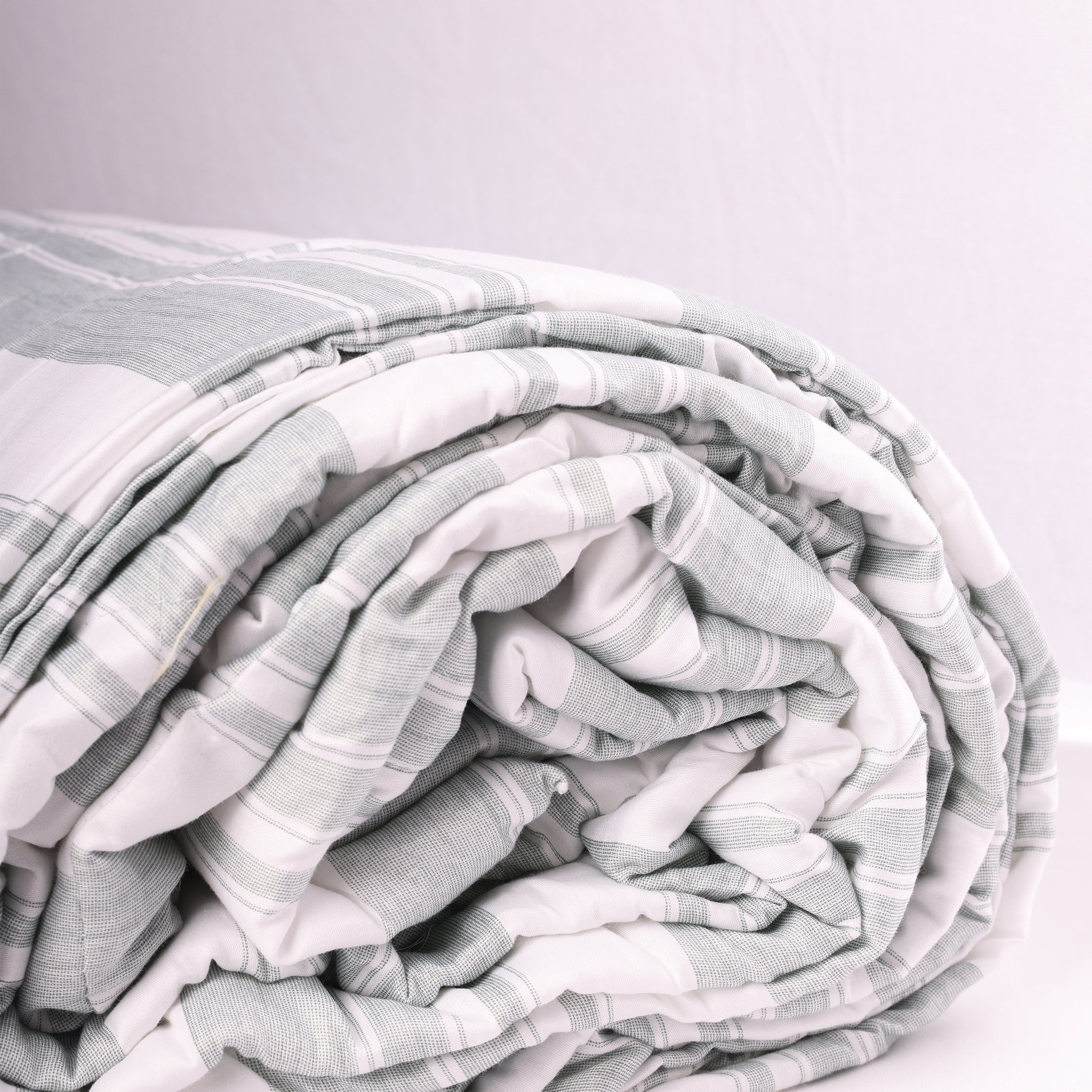 Folded double bed comforter with ash green stripes on white base. Buy winter comforter online.