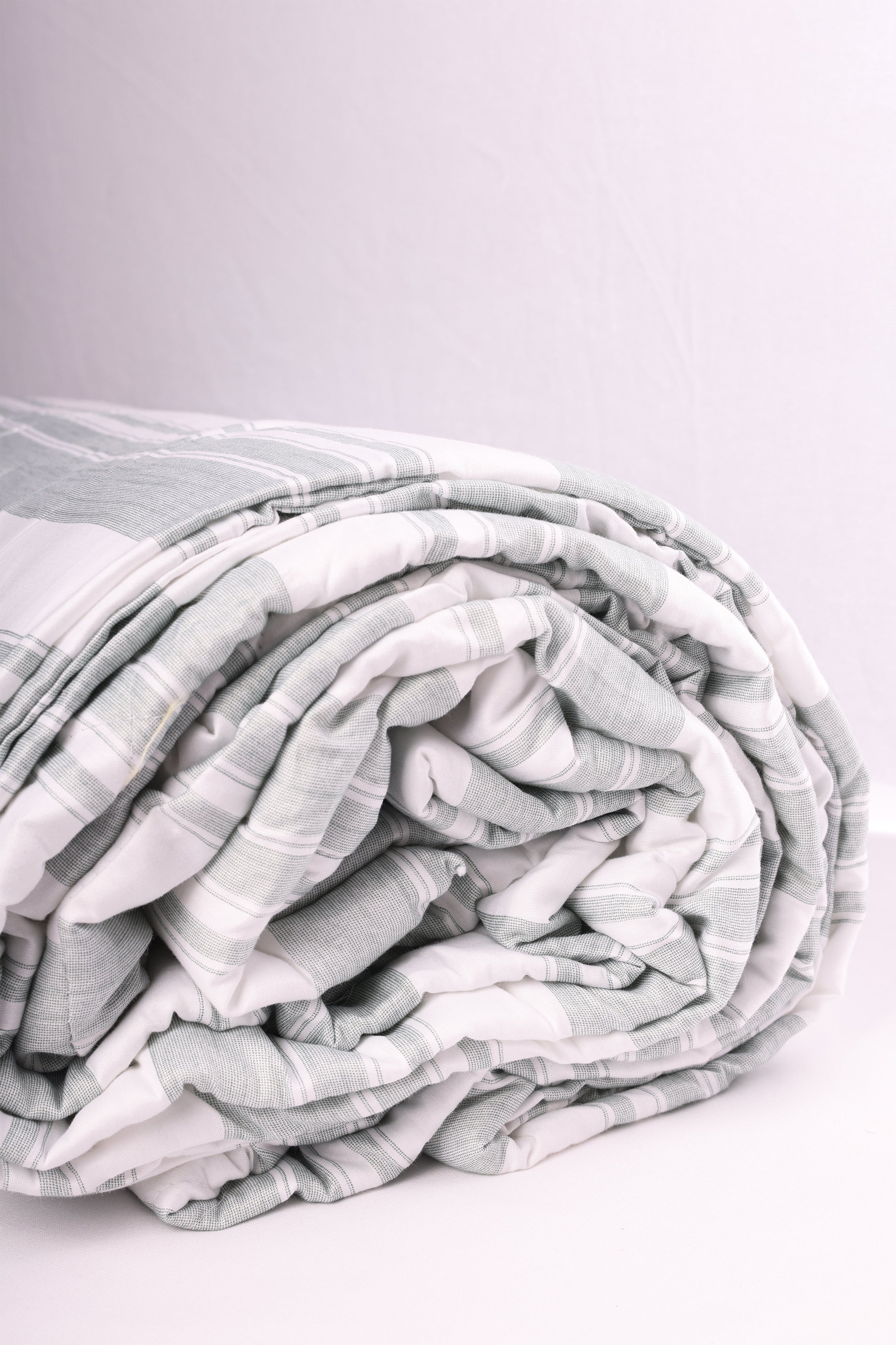 Folded double bed comforter with ash green stripes on white base. Buy winter comforter online.