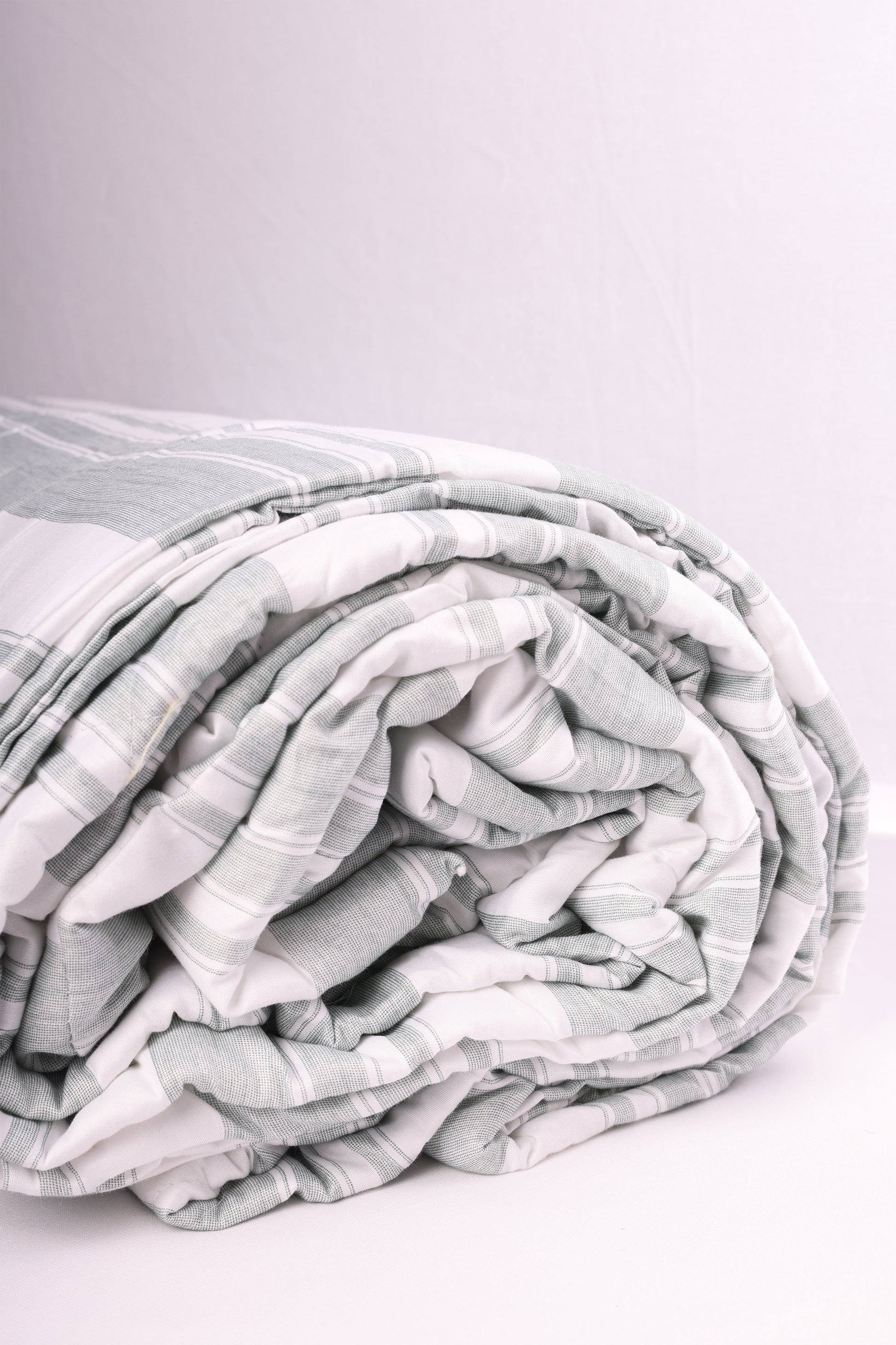 Folded double bed comforter with ash green stripes on white base. Buy winter comforter online.