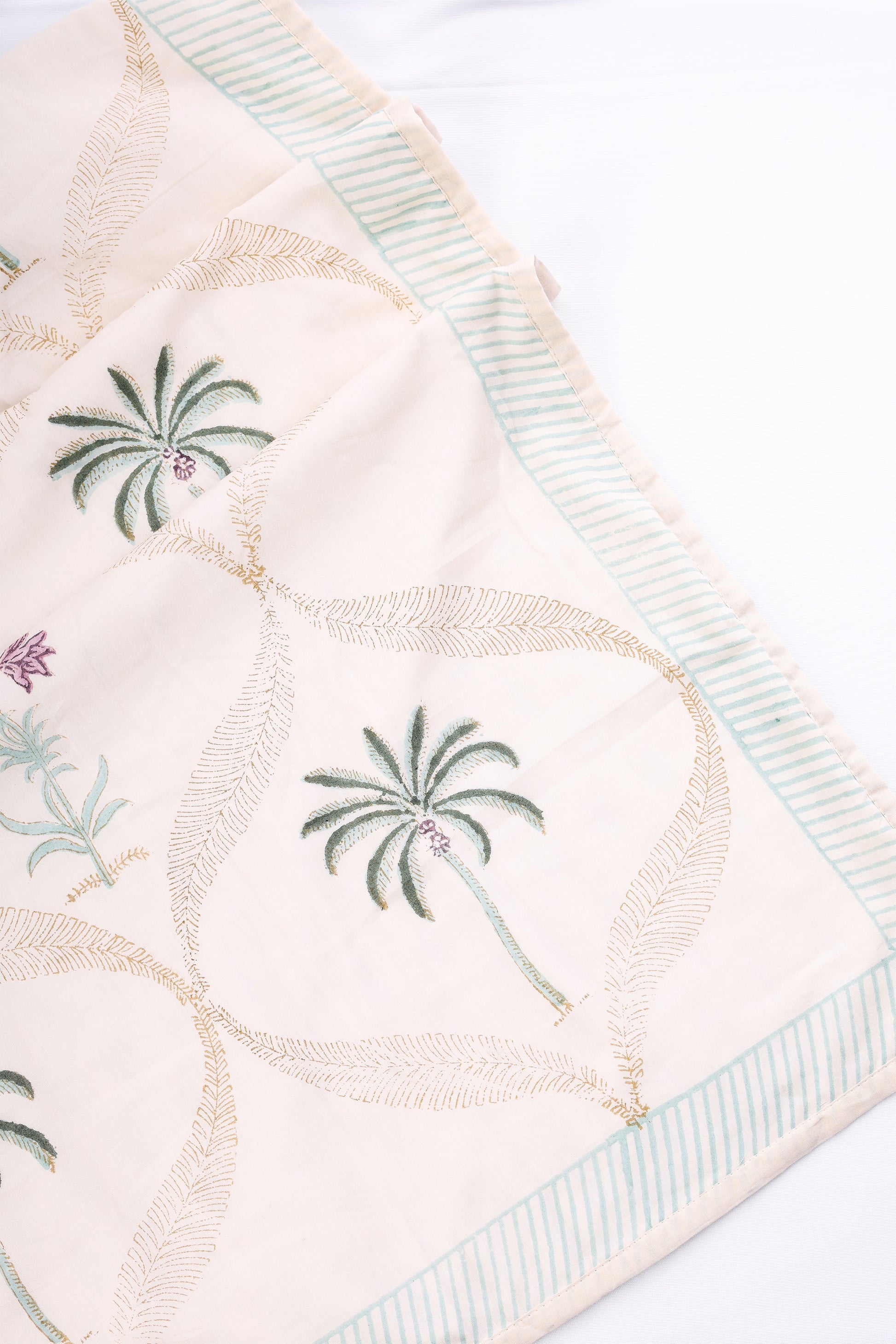 Light yellow AC Dohar blanket with palm tree designs on a white background