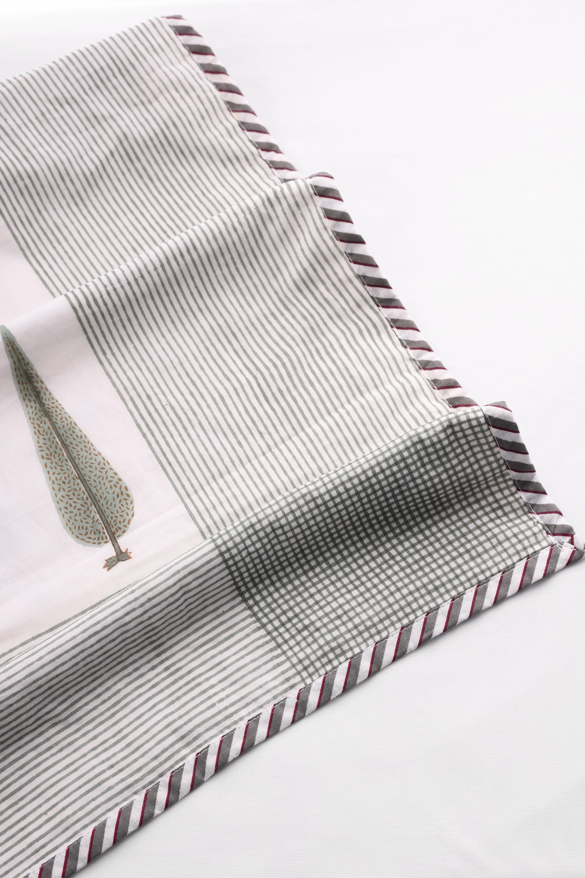 Close-up of a cotton dohar blanket with striped and checkered print on a white background. Buy summer blanket.