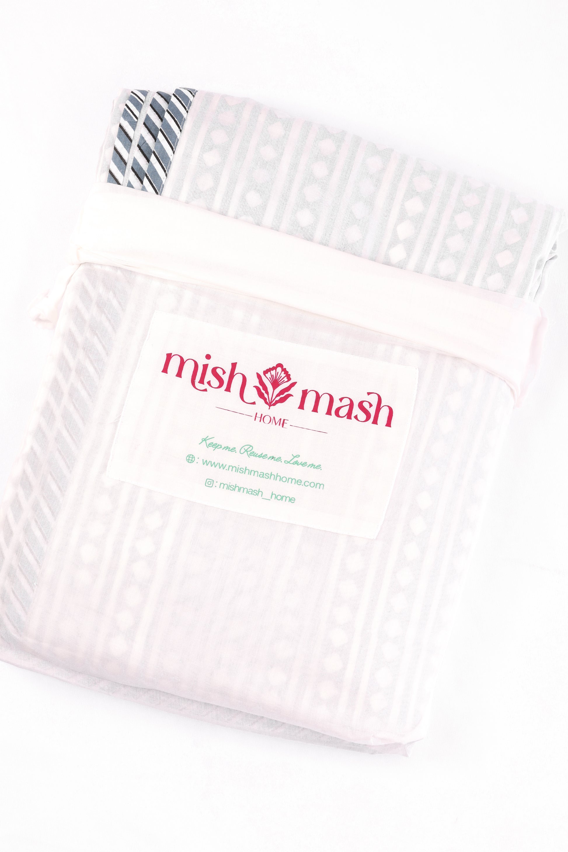 White cotton dohar blanket in a white cotton bad with 'mishmash' branding on a white background. buy dohar online.