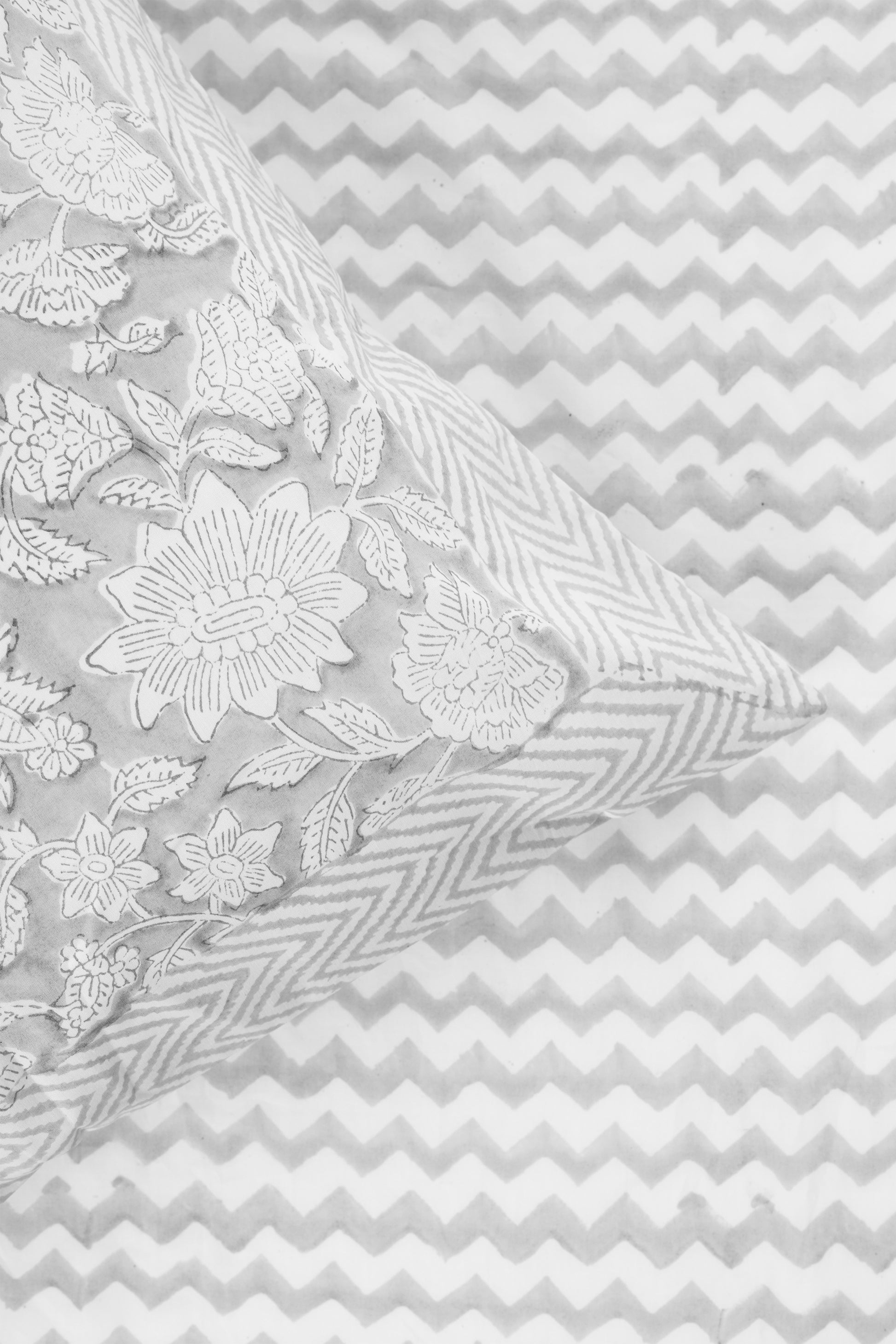 Floral grey pillow on a pure cotton grey bed sheet