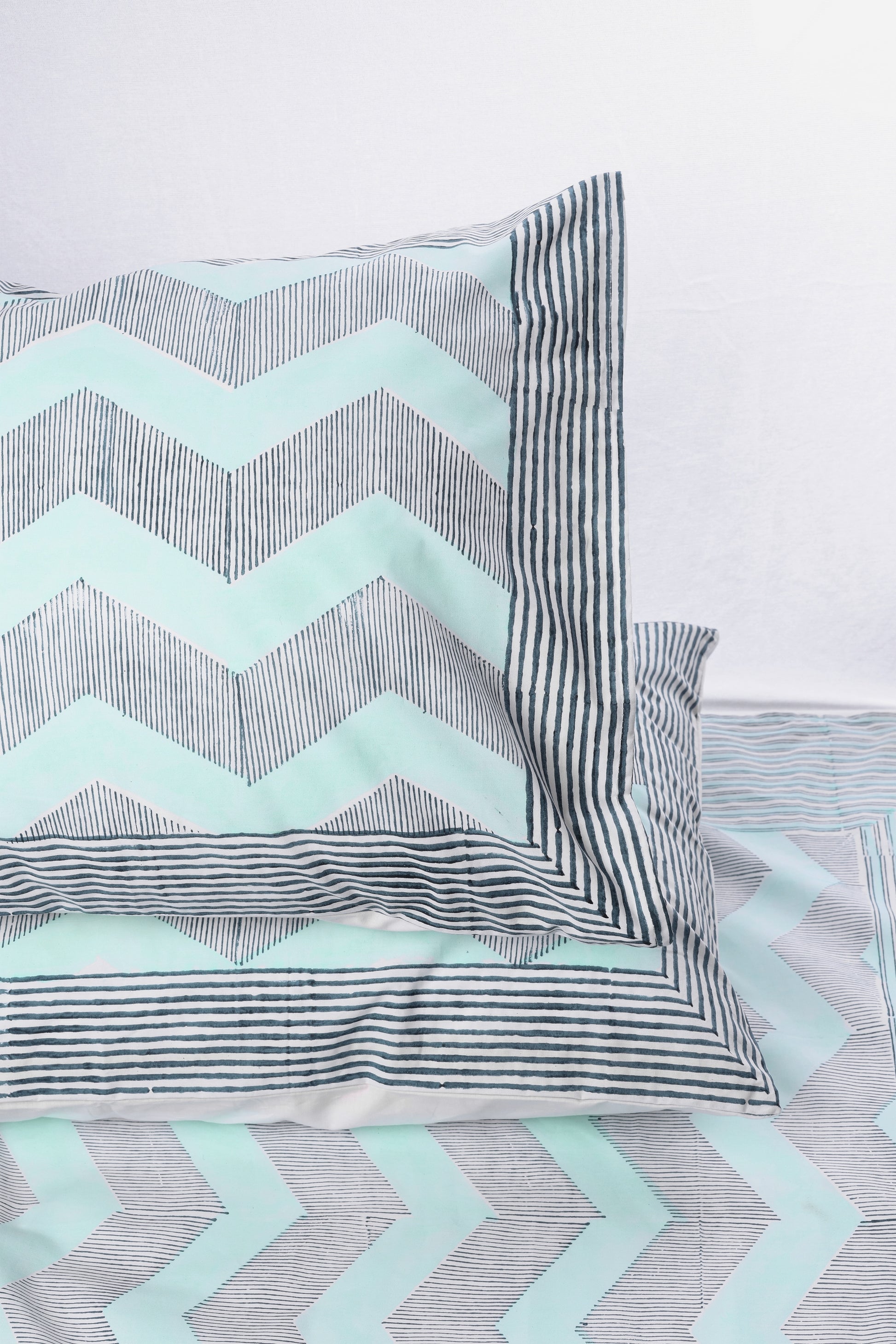 Set of pillows with chevron and striped patterns on a blue cotton double bed sheet