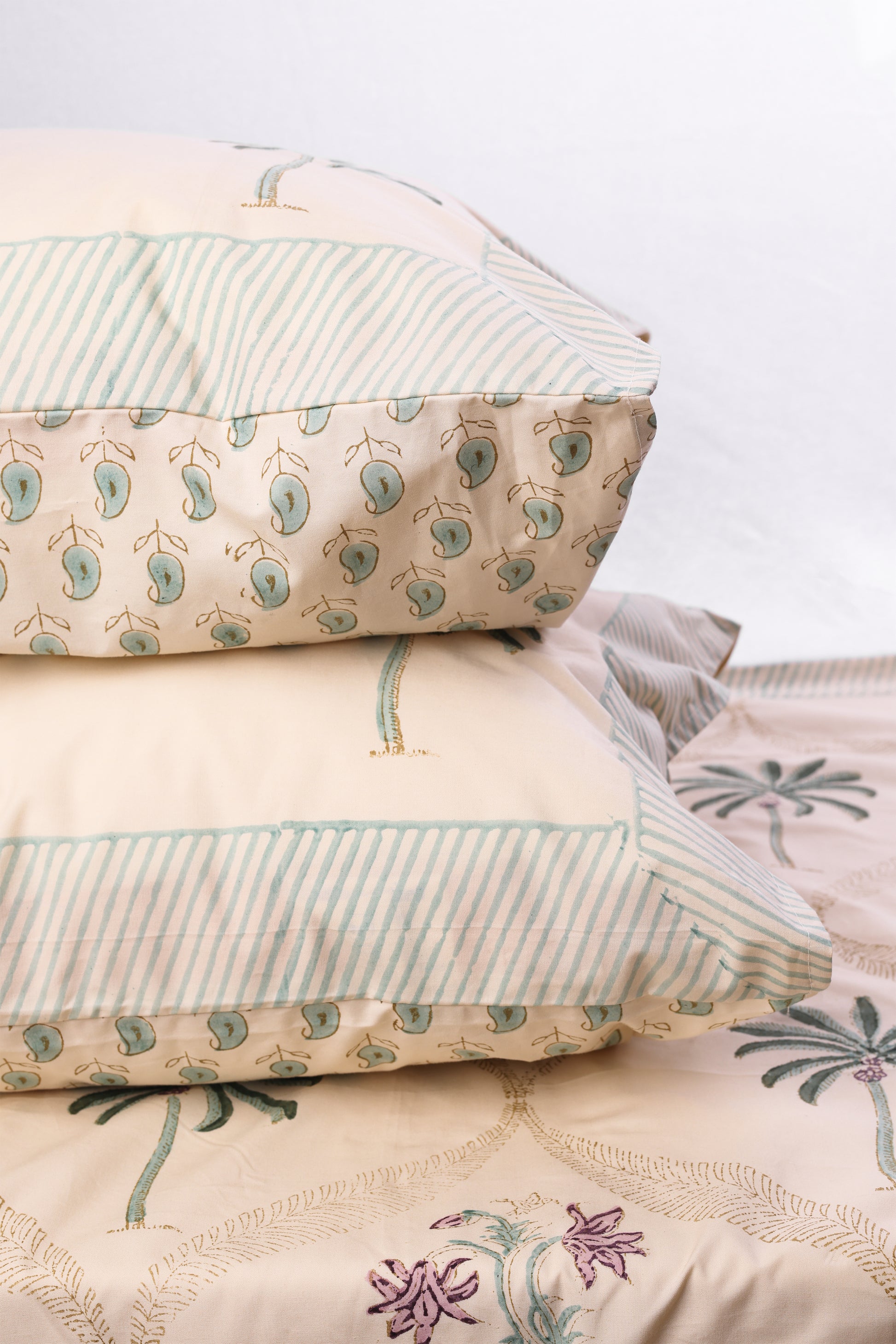 Stack of pure cotton pillows on a double bedsheet with a neutral background