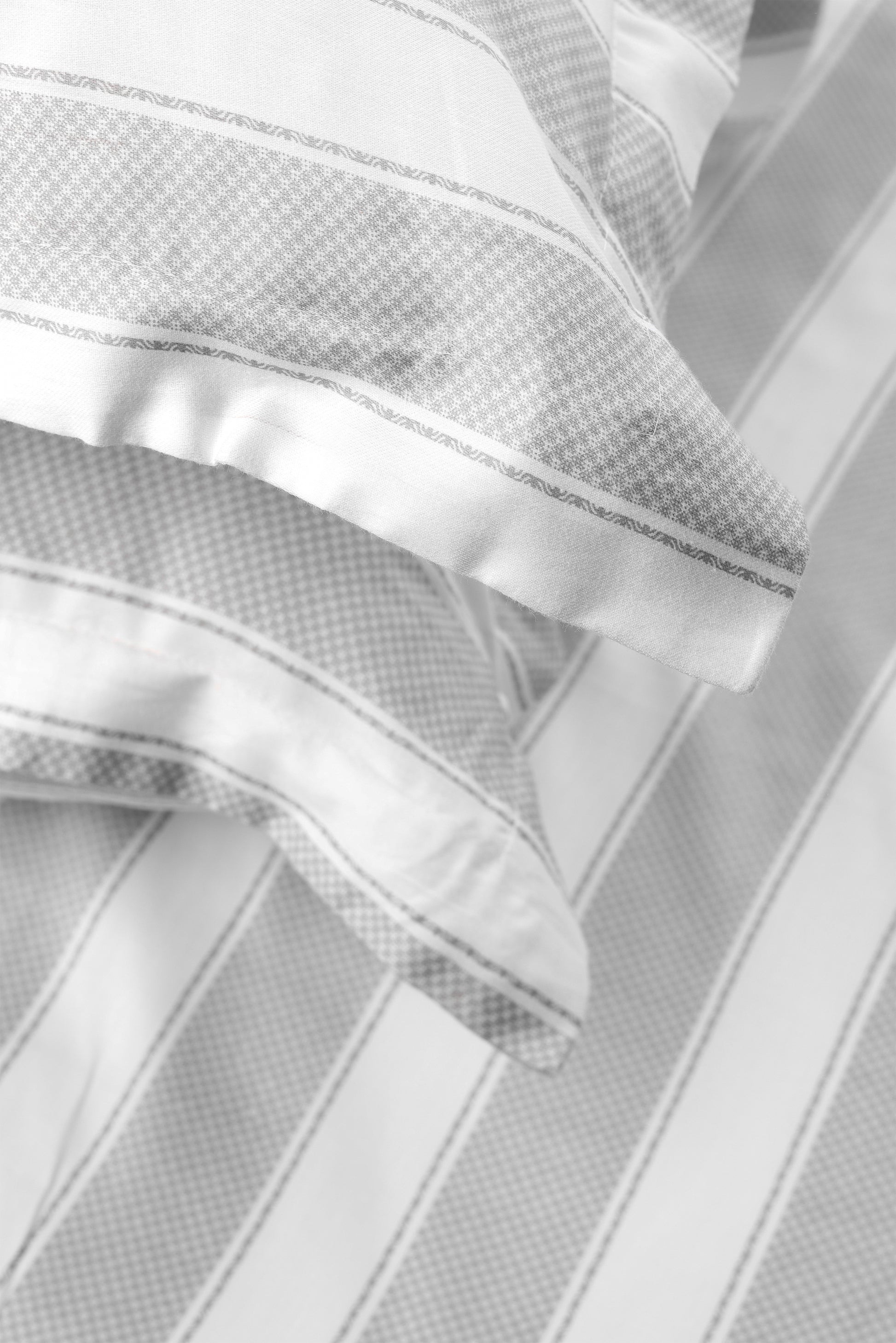 Close-up of a double bed sheet white and grey with two striped pillow covers