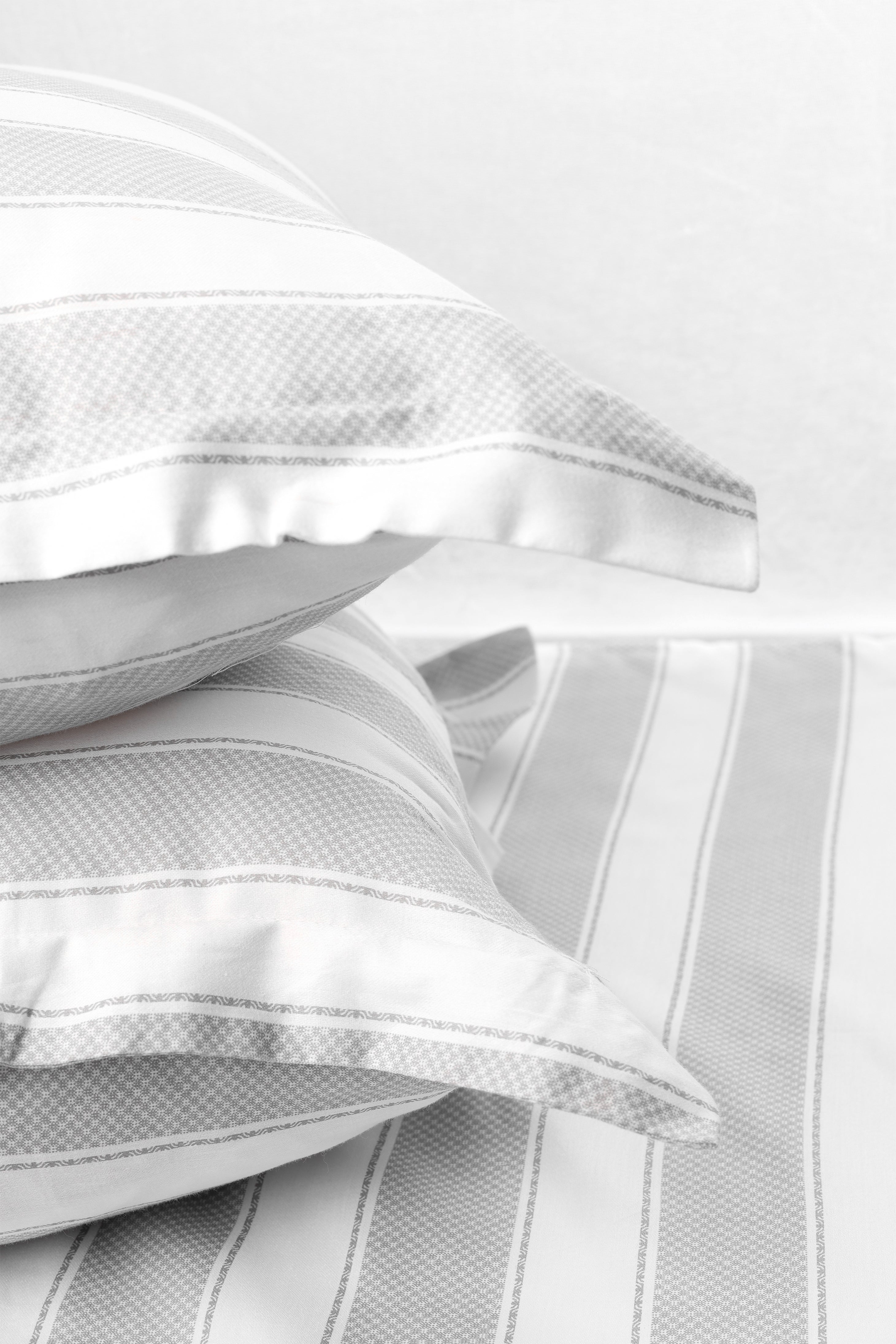 Stack of two white and grey pilows with pure cotton 400 tc double bed bedsheet in king size