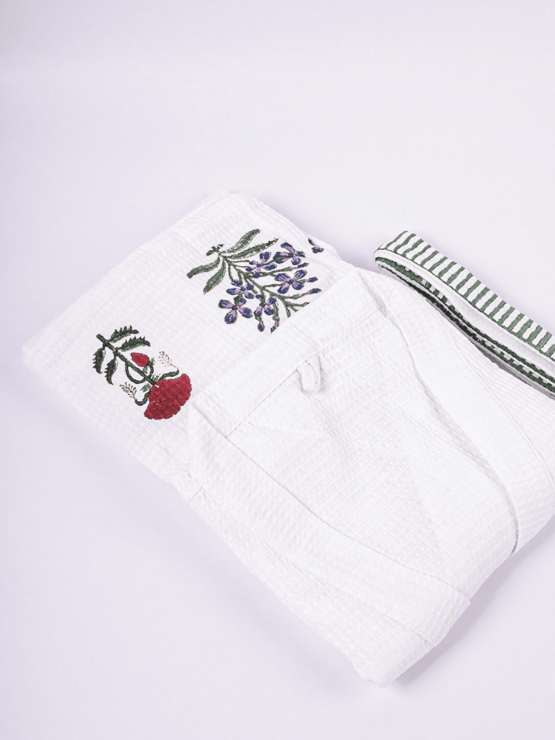 A folded white waffle cotton bathrobe featuring hand block printed floral motifs