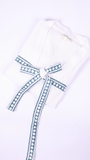 A folded white cotton robe with a long tie belt featuring a blue and white geometric pattern