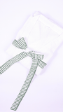 A folded white bathrobe with a green and white striped belt