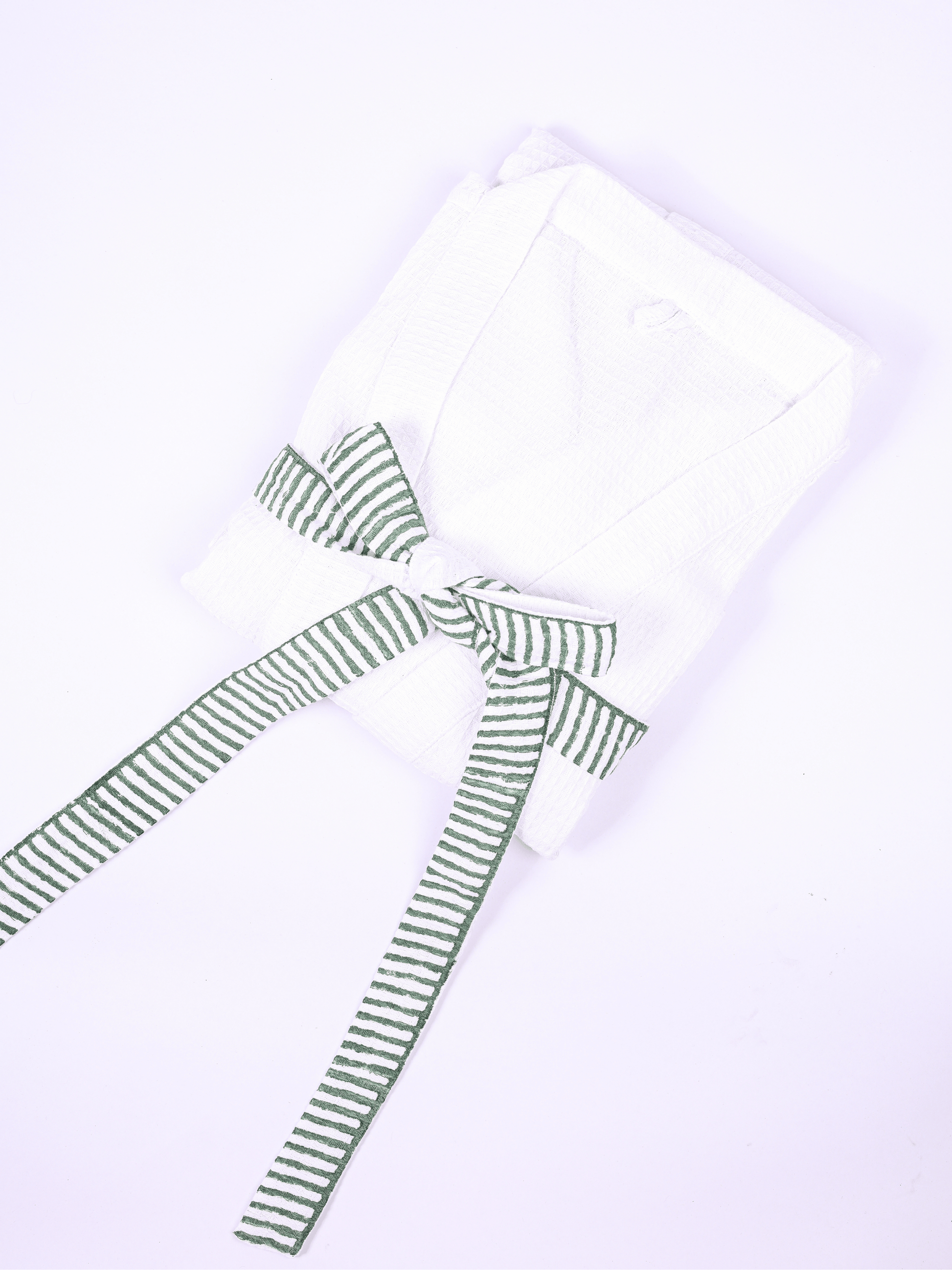 A folded white bathrobe with a green and white striped belt
